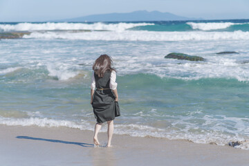 綺麗な海の波打ち際を歩く女性