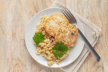 Chicken or vegetable cutlets with a side dish of bulgur in a plate on the table. Diet nutrition. Top view
