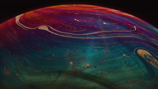 Fluid soap bubble looking like planets. Psychedelic colorful abstract art with urreal patterns of color in motion.
