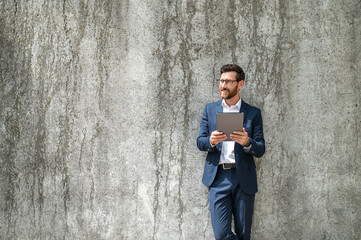 Obraz na płótnie Canvas One man in a suit standing near the grey wall