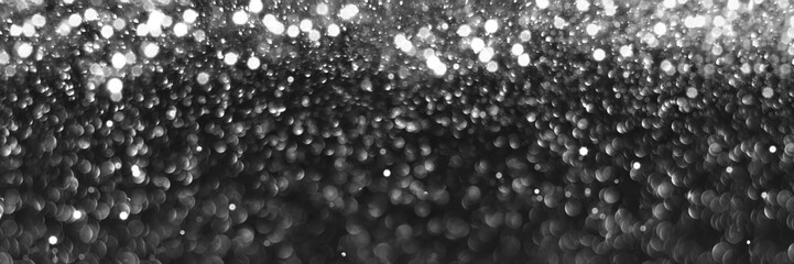 Gray black sparkling glitter bokeh background, abstract defocused texture. Holiday lights. Snowy...