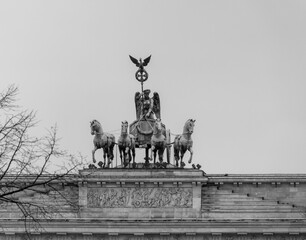 Grayscale shot of the chariot statue on the Brandenburg Gate in Berlin, Germany under a clear sky