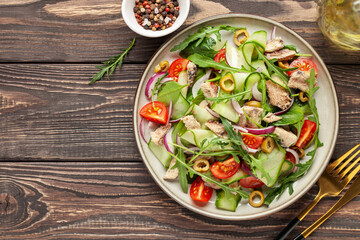 Fresh salad with vegetables and fish. Arugula, spinach, cucumbers, tomato, onions and fish in a plate on the table. Diet nutrition. Top view. Copy space