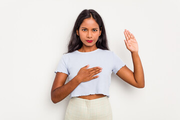 Young Indian woman isolated on white background taking an oath, putting hand on chest.