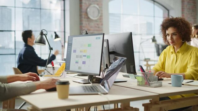 Multiethnic Group of Creative Colleagues Working on Computers During Day in a Modern Bright Office. A Biracial Woman Smiles Happily After Successfully Finishing a Work Project. Dolly Shot