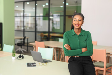 Successful young african-american female entrepreneur, small business owner, female office employee, black businesswoman wearing green casual shirt stands in confident pose with arms crossed