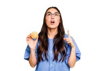 Young caucasian physiotherapist woman holding a tennis ball isolated isolated on green chroma background pointing upside with opened mouth.