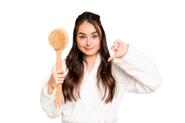 Young caucasian woman holding shower brush isolated on green chroma background showing a dislike gesture, thumbs down. Disagreement concept.