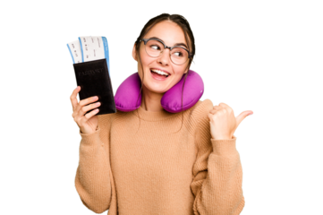 Young caucasian woman with inflatable travel pillow holding passport isolated on green chroma background points with thumb finger away, laughing and carefree.