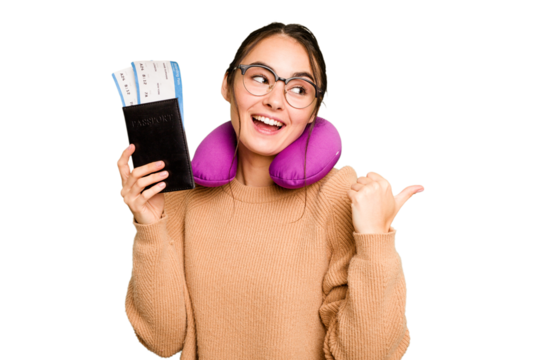 Young caucasian woman with inflatable travel pillow holding passport isolated on green chroma background points with thumb finger away, laughing and carefree. - Powered by Adobe