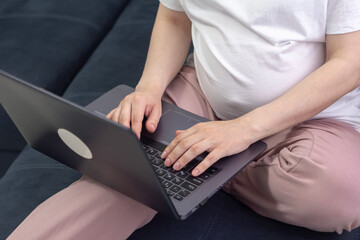 Pregnant woman working on laptop at home