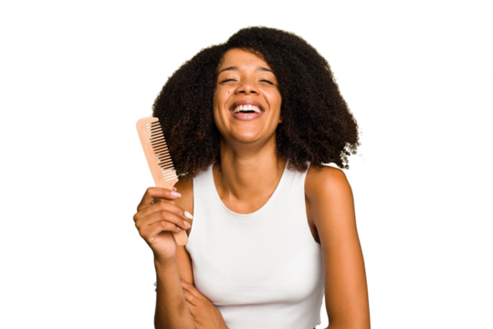 Young african american woman holding hair comb isolated laughing and having fun.