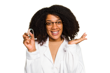 Young otorhinolaryngologist African american woman holding hearing aid isolated showing a copy space on a palm and holding another hand on waist.