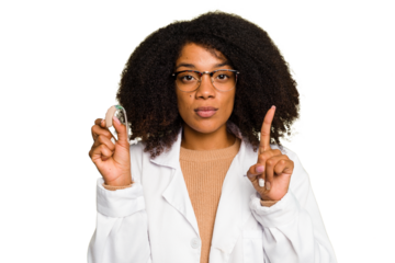 Young otorhinolaryngologist African american woman holding hearing aid isolated showing number one with finger.