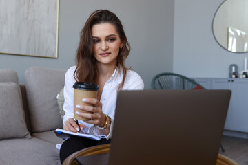 Young woman sitting on the couch and studying online at home