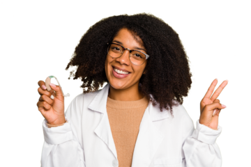 Young otorhinolaryngologist African american woman holding hearing aid isolated joyful and carefree showing a peace symbol with fingers.