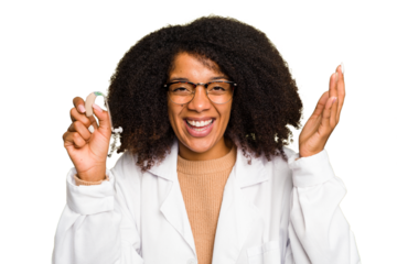 Young otorhinolaryngologist African american woman holding hearing aid isolated receiving a pleasant surprise, excited and raising hands.