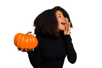 Young African American woman holding a pumpkin for halloween day isolated shouting and holding palm near opened mouth.