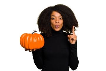 Young African American woman holding a pumpkin for halloween day isolated having some great idea, concept of creativity.