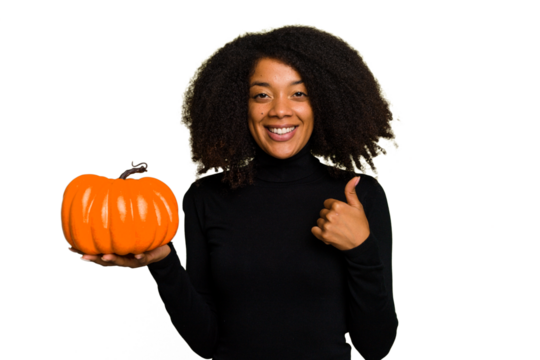 Young African American woman holding a pumpkin for halloween day isolated smiling and raising thumb up