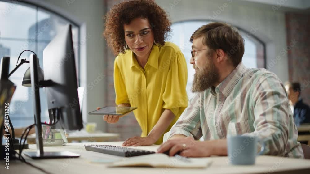 Poster Portrait of Two Creative Colleagues Collaborating and Pointing at the Computer in Modern Office. Biracial Female Chief Manager Uses Tablet to Advice Work to a Software Engineer. Slow Motion.