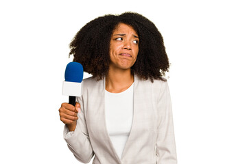 Young TV presenter African American woman with a microphone isolated confused, feels doubtful and...