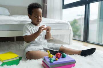 Cute little boy making things from plasticine on the ground Follow your imagination with a smiling.