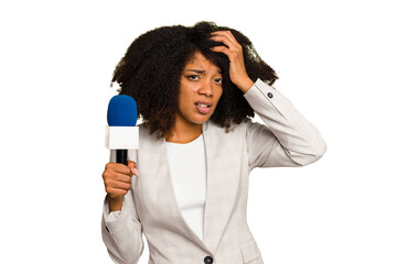 Young TV presenter African American woman with a microphone isolated being shocked, she has...