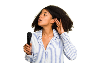 Young African American singer woman holding a microphone isolated trying to listening a gossip.