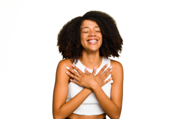 Young African American woman isolated laughs happily and has fun keeping hands on stomach.