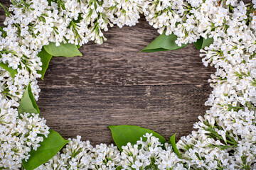Frame of white lilac flowers on an old wooden background, copy space