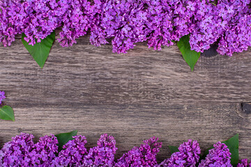 Frame of purple lilac flowers on an old wooden background, copy space