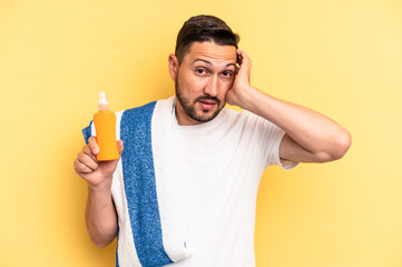 Young latin man ready to go to the beach holding a solar skin protection isolated being shocked,...