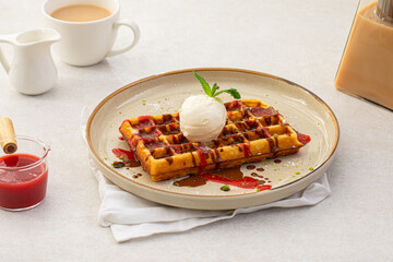 Portion of sweet belgian waffles with ice cream and jam