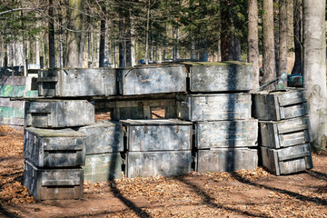 Wall made of chests and Paintball trunks to hide, fortification among the trees. Arena for shooting colored paint balls.