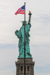 Back view of Liberty Statue with stars and stripes flag waving