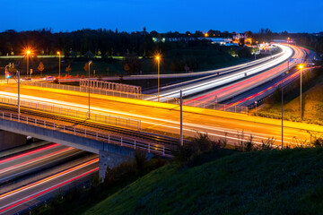 German Motorway junction in Bochum. Streets and bridge at dusk with light traces of passing cars and tram at evening blue hour in Ruhr Basin. A 40 connecting Dortmund, Essen and Duisburg at rush hour.