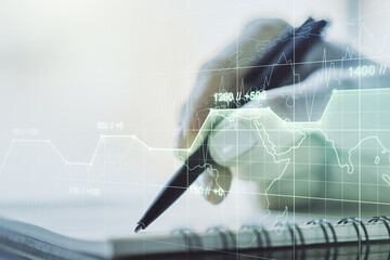 Double exposure of abstract creative statistics data hologram with woman hand writing in notepad on background, analytics and forecasting concept