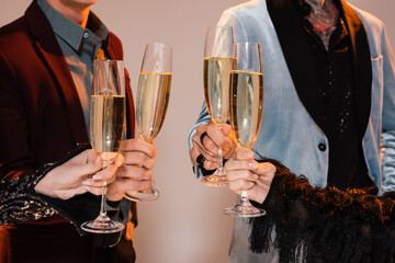 cropped view of people in elegant clothes holding champagne glasses on grey background