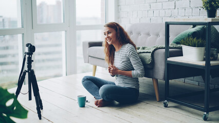 Beautiful young woman vlogger is talking and gesturing recording video with professional camera for...
