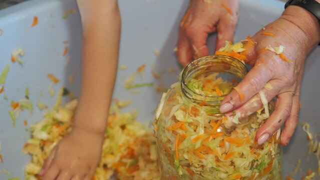 Home canning. The child helps to preserve cabbage and puts it in a glass jar. Hand held. Siberia.