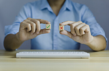 businessman's hand holds a wooden block showing checks marks and wrong