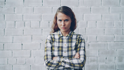 Portrait of angry young lady looking at camera, frowning and shaking her head expressing disappointment and disapproval standing with arms crossed and breathing heavily.