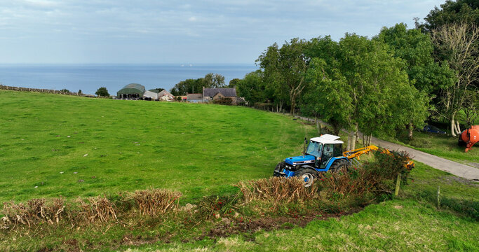 Aerial photo of a Blue New Holland Ford 8240 Tractor Cutting a hedge with a McConnel on a farm in UK Antrim Northern Ireland 30-10-22