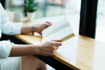 Portrait of a beautiful Asian female employee reading a book during her lunch break