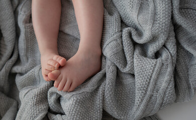 Banner of new born tiny feet on pastel blanket. Unrecognisable kid in the bed. Close up, copy space. 