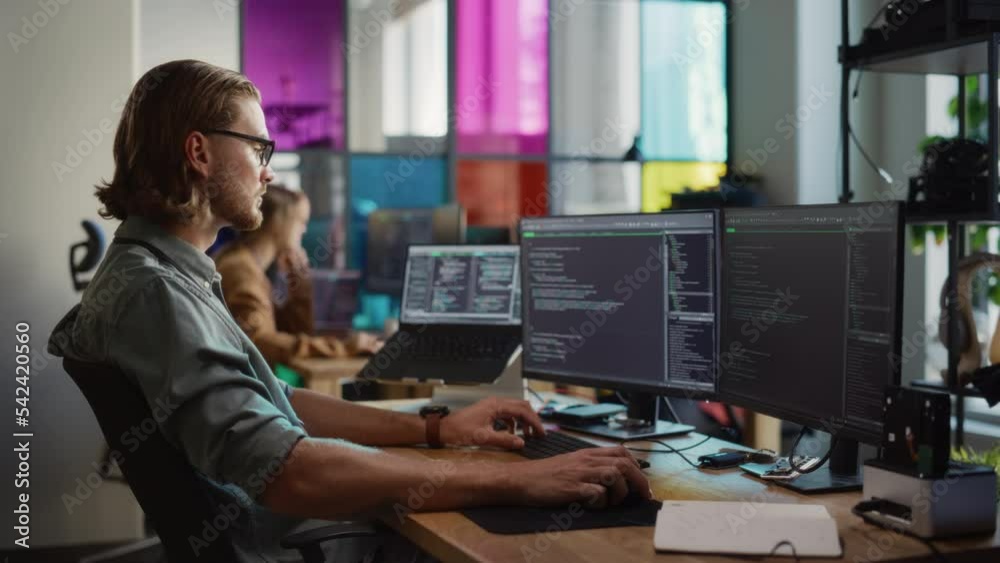 Aufkleber Young Caucasian Man Coding on Personal Computer and Laptop Set Up In Stylish Office. Professional Programmer Developing Innovative AI Software in Technological Start-Up, Using Multiple Displays.