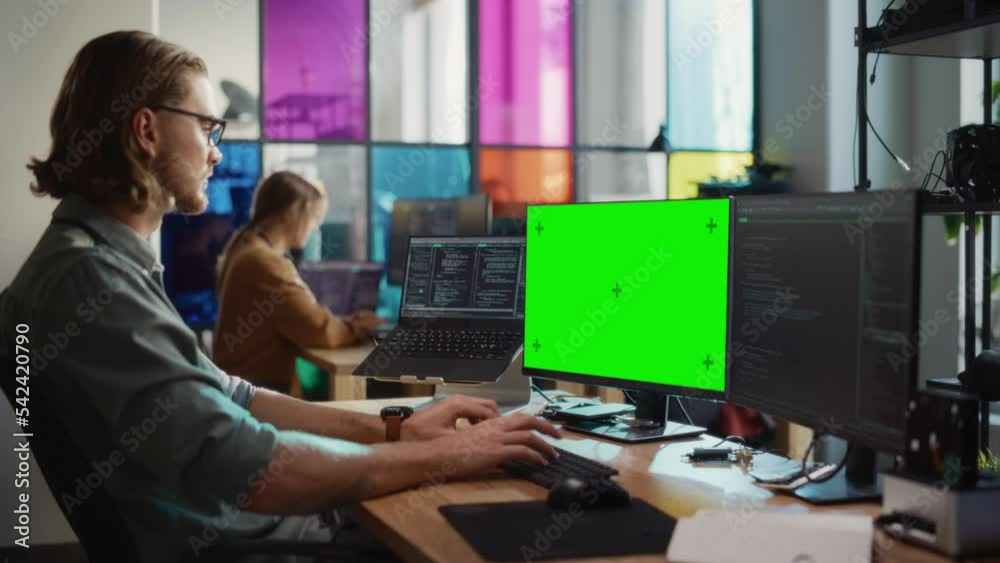 Leinwandbilder Male Programmer Writing Code and Using Desktop Computer With Mockup Green Screen Chromakey on Display in Modern Office. Caucasian Man Working on Application Development For Innovative Digital Service.