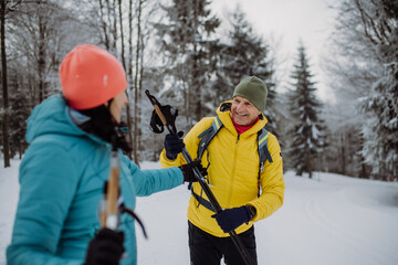 Senior couple skiing together in the middle of forest