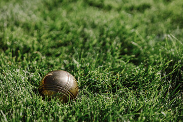 A golden metal ball for the game lies on green grass and shimmers in the sun
